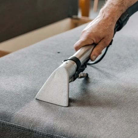 Fabric ottoman being cleaned with an upholstery tool